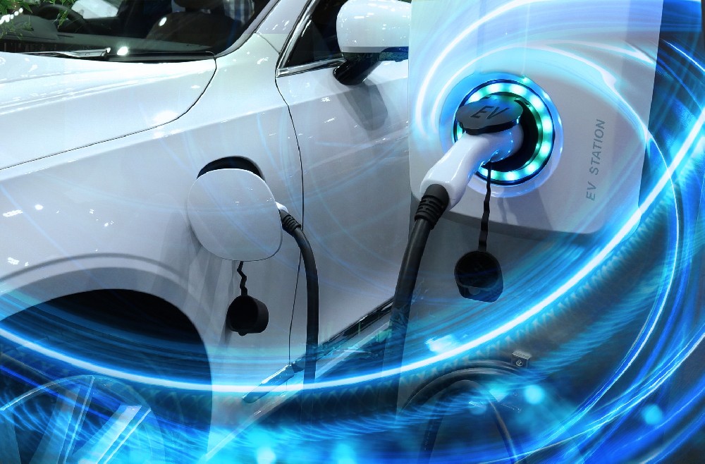 EV Car or Electric vehicle at charging station with the power cable supply plugged in on blurred nature with blue enegy power effect